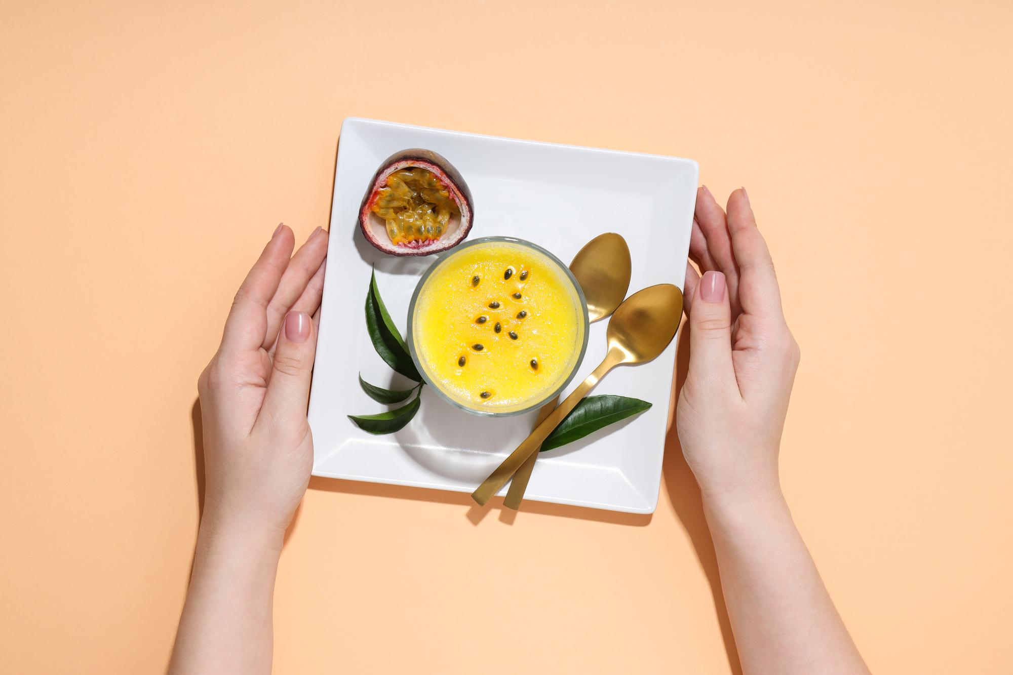 hands plating a composed dish in a bright kitchen
